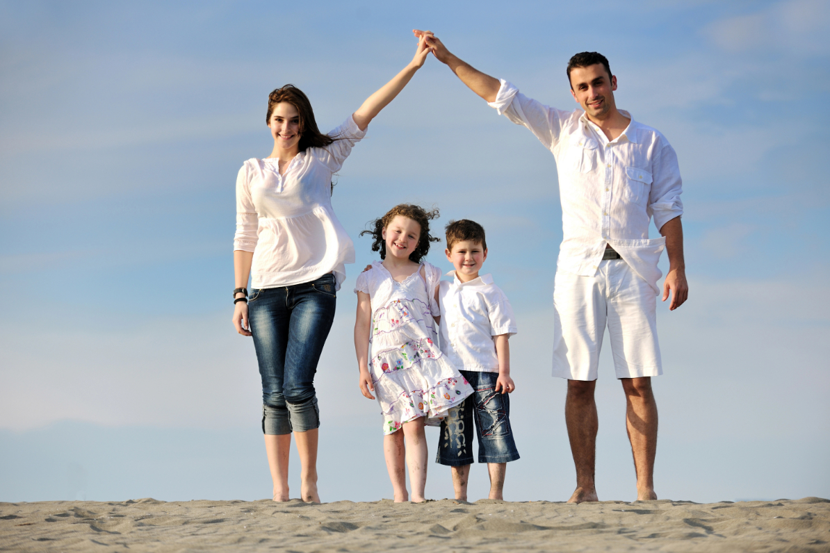 Family on beach showing home sign